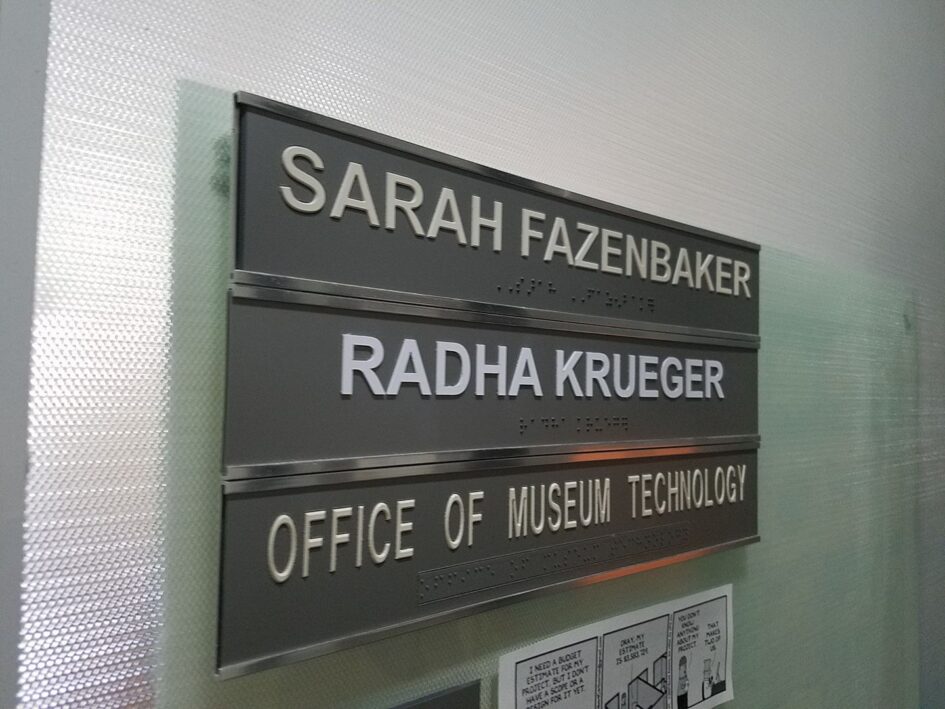 name plates on a wall in an office that have two names above the title Office of Museum Technology