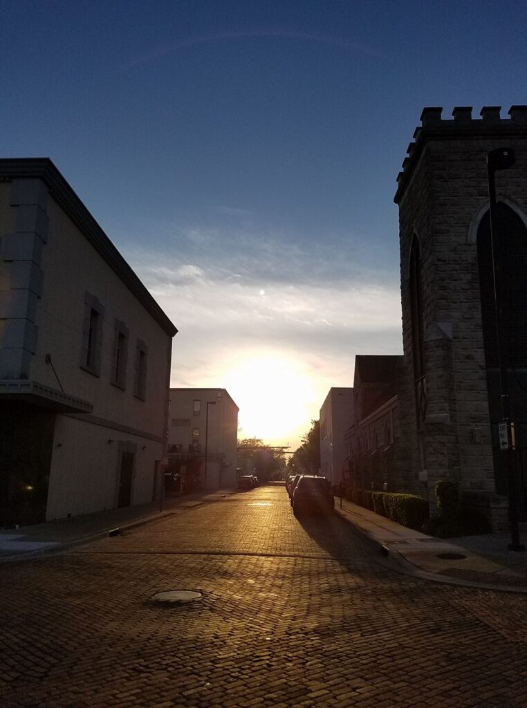 setting sunlight is reflecting on a brick street between two buildings