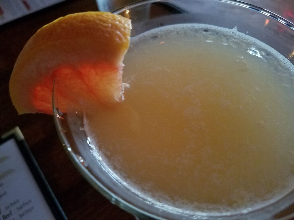 a cloudy cocktail with a grapefruit wedge in it
