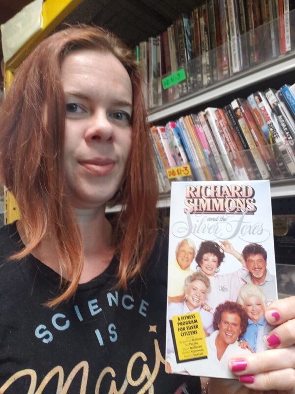 a selfie of a person holding a Richard Simmons workout VHS tape