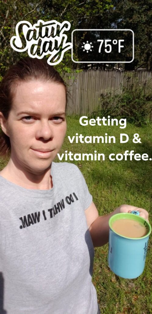 a selfie of someone holding coffee in a sunny yard