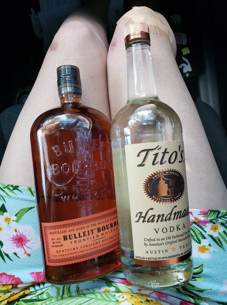 a bottle of bourbon and a bottle of vodka are sitting on someone's lap