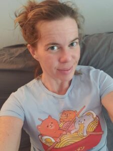 selfie of a person with a shirt printed with cats in a ramen bowl