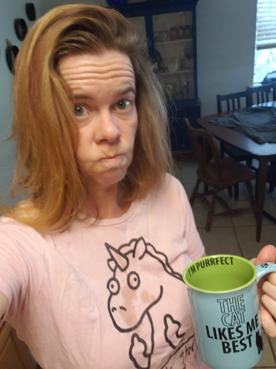 selfie of a person making a face and holding a coffee cup up near obvious wet spots on their shirt