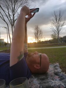 a person is laying on their back on a lawn holding their phone up over their face