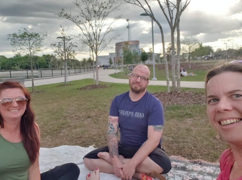 selfie of thee people sitting on blankets in a park
