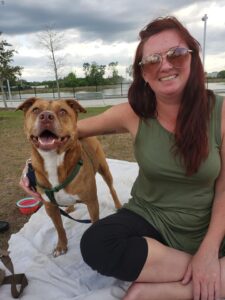 a person and a dog sitting on blankets in the park