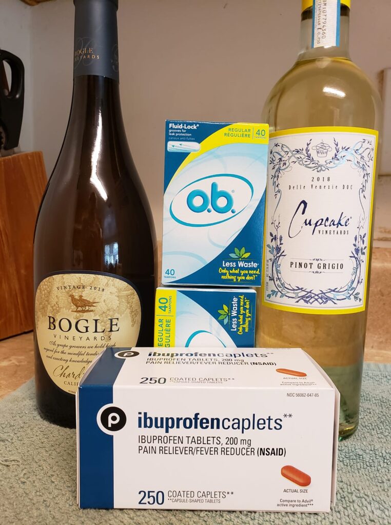 two bottles of wine with a box of tampons and a box of ibuprofen