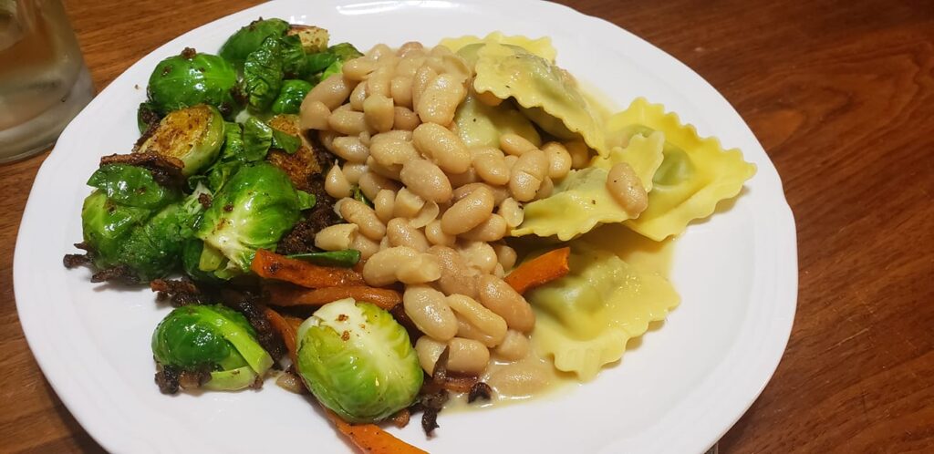 a plate of food that looks like ravioli, brussels sprouts and beans