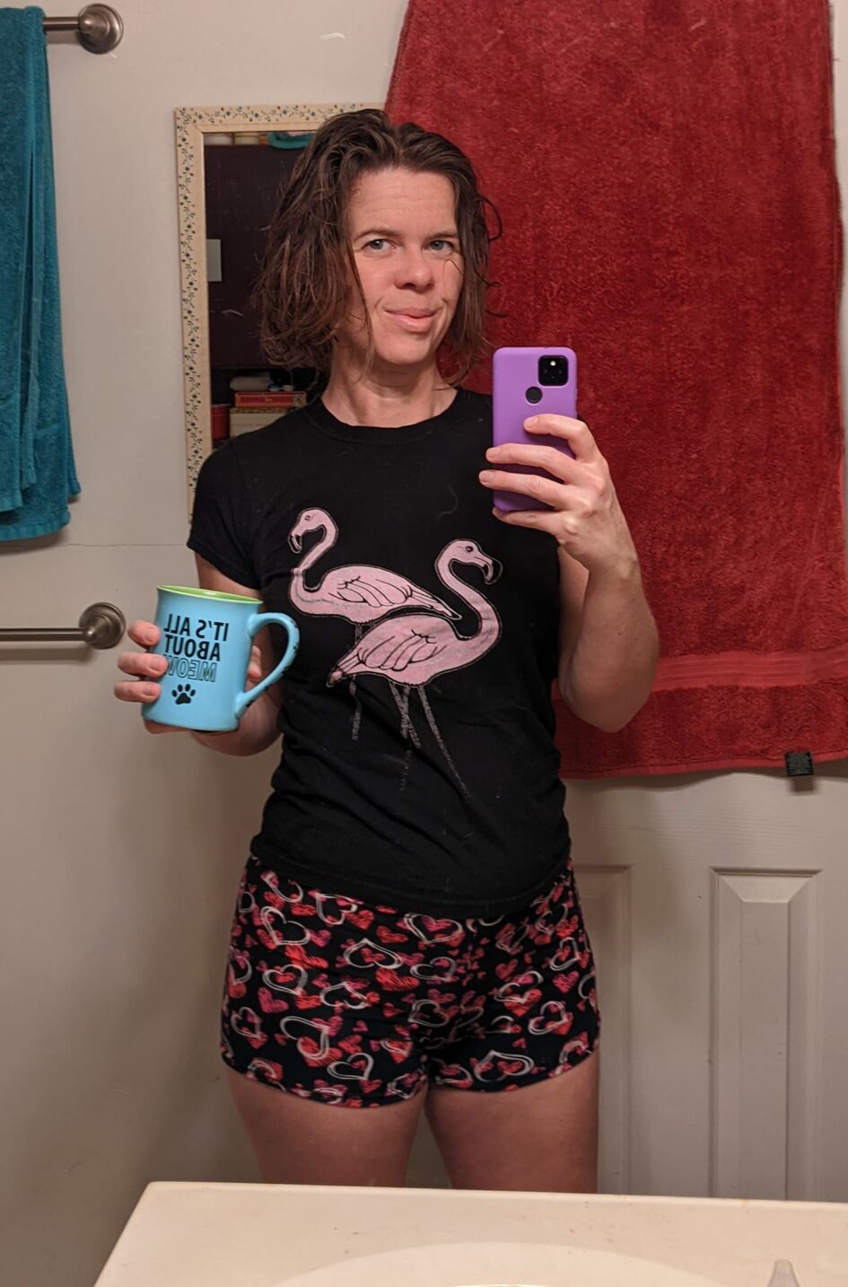 bathroom selfie of a person in casual clothes and holding a coffee mug