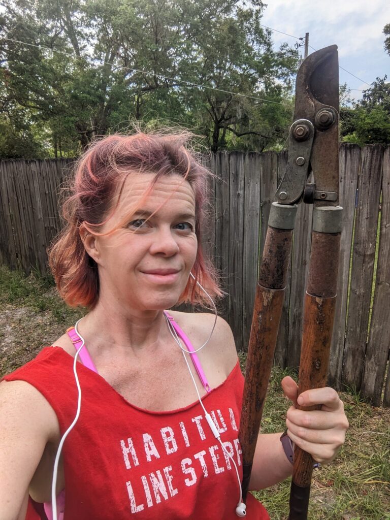 selfie of a person clearly doing yard work with messy hair and holding branch clippers
