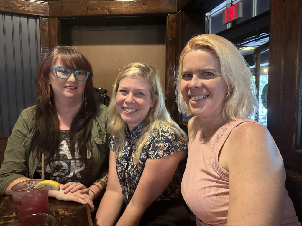 three people smile for the camera in a restaurant