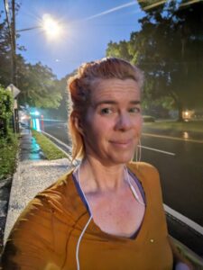 a person is running at night with wet streets in the background and a wet shirt