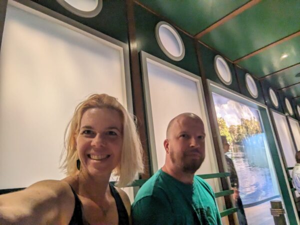 two people are in some kind of long room with frosted windows with round windows above them like a river boat