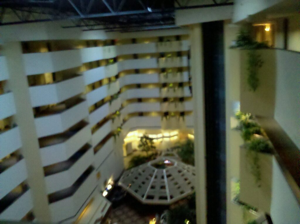 a blurry shot of the atrium of a hotel building showing the bands of balconies for many floors below
