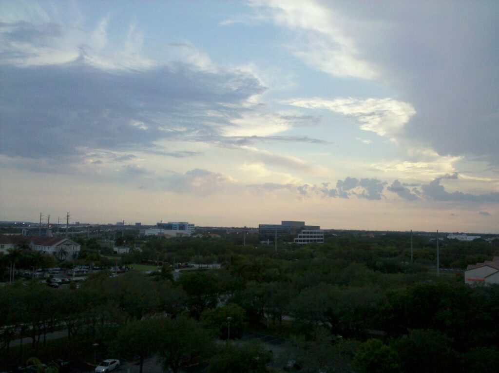 a landscape view of what seems to be trees dotted by parking lots and hotels with a hazy sky overhead