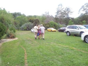 three people are walking together arm in arm over a grassy parking lot