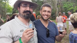 two men are holding small beer glasses outside