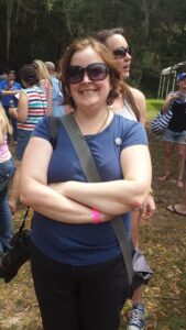 a person with a camera on a strap has her arms crossed