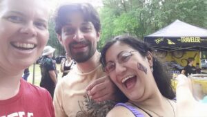 selfie of three people at some kind of outdoor event with beer tents