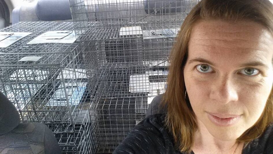 selfie of a person with stacks of what look like wire boxes behind her in a small space