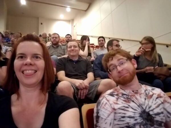 a groups shot of a dozen people in theater seating making faces