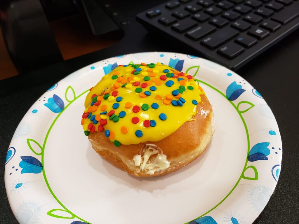 a donut has jaunty yellow icing and confetti on it