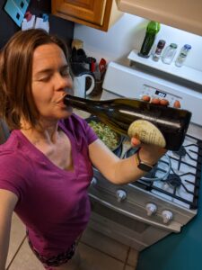 selfie of a person cooking and sipping directly from the wine bottle