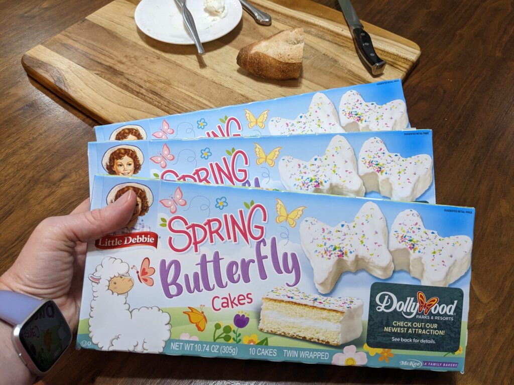 hand holding three boxes of Little Debbie butterfly cakes