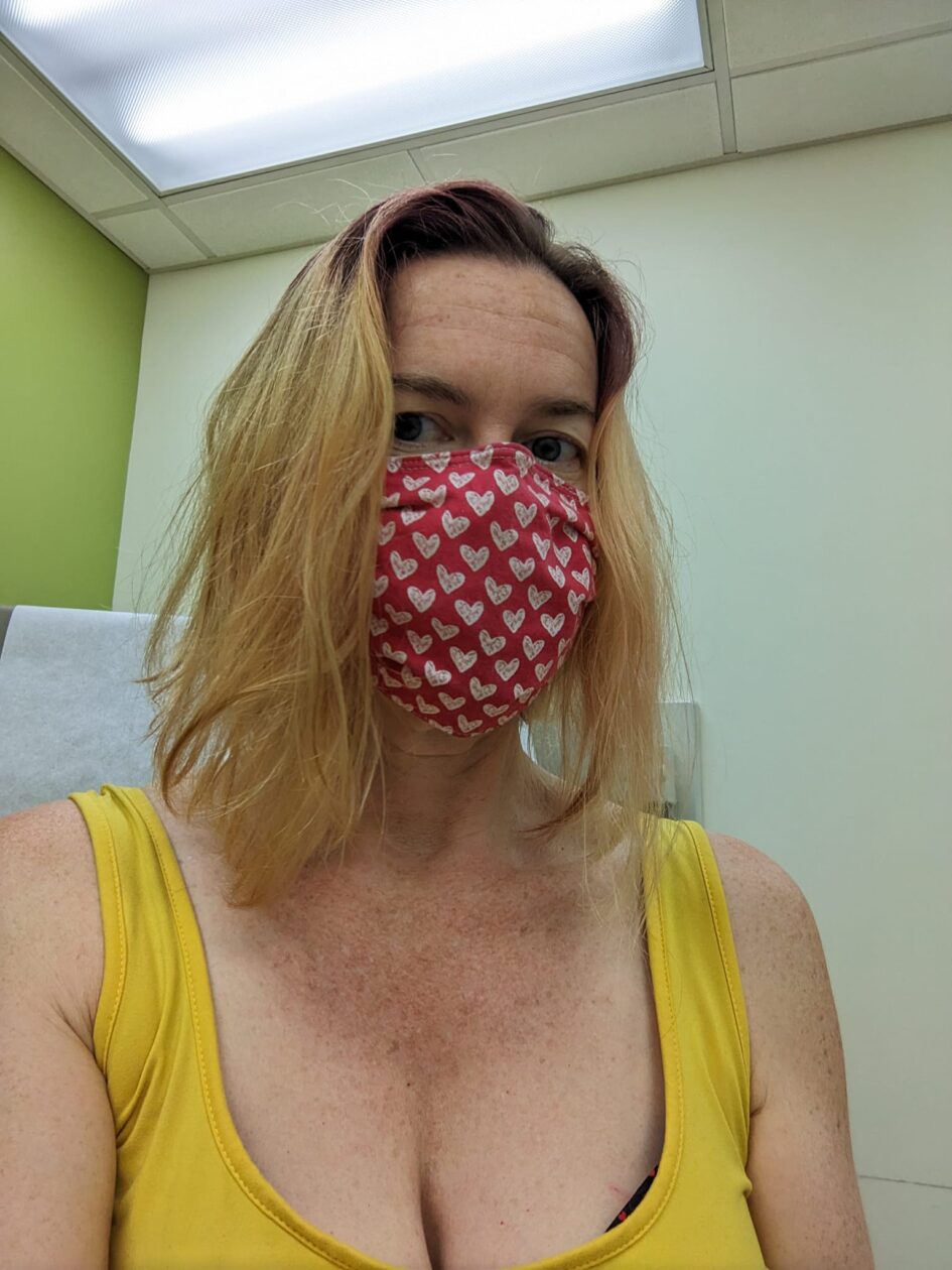 selfie of a person wearing a mask and sitting in what could be a doctor's office