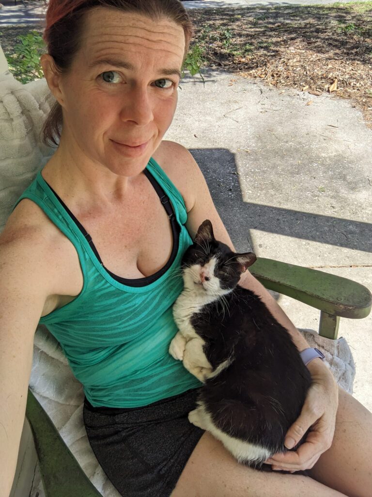 selfie of a person in a chair holding a happy looking black and white cat in her lap