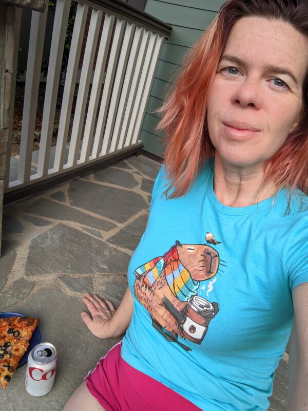 selfie of a person sitting on a porch next to a slice of pizza