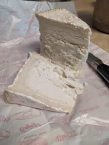 a triangular wedge of soft creamy cheese of some kind on a paper wrapper