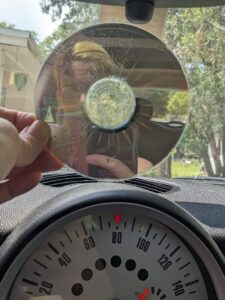 a hand holding up a CD against a dash board