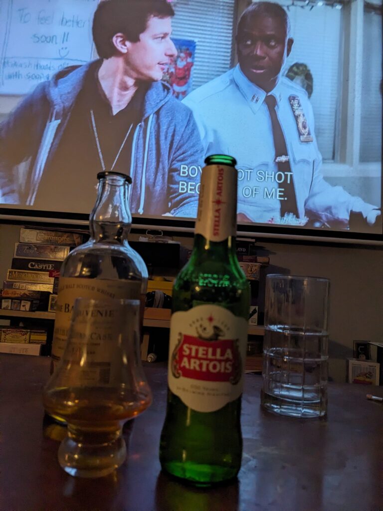 there are beer bottles on a table and two men on the TV