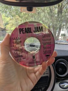 a hand holding up a Pearl Jam CD