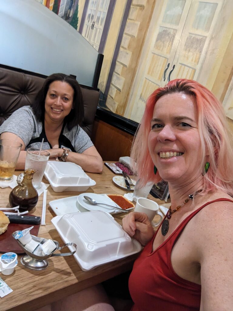 selfie of two people at a cluttered diner table