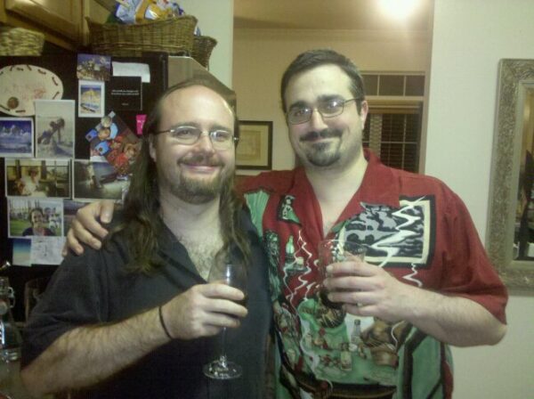 two people are posing for a photos holding wine glasses