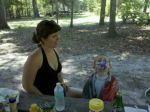 an adult is smiling at a child sitting at a picnic table