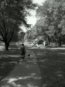 an adult and small child are walking on a path in a park