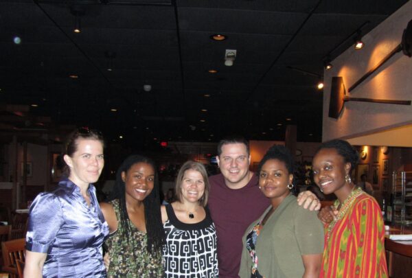 a group of six people pose for a shot in a dark restaurant