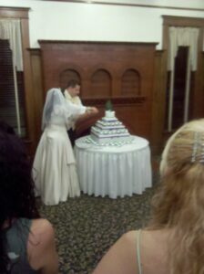 blurry photo of a bride and groom cutting a big white cake