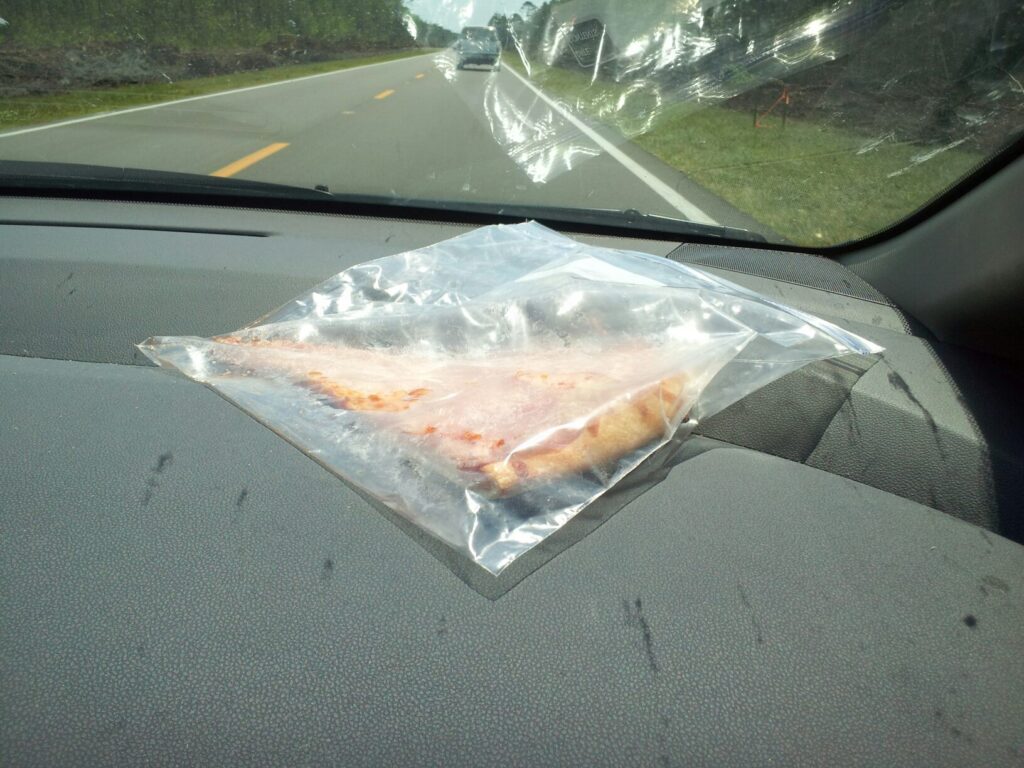 a piece of pizza is in a bag on a car dash board