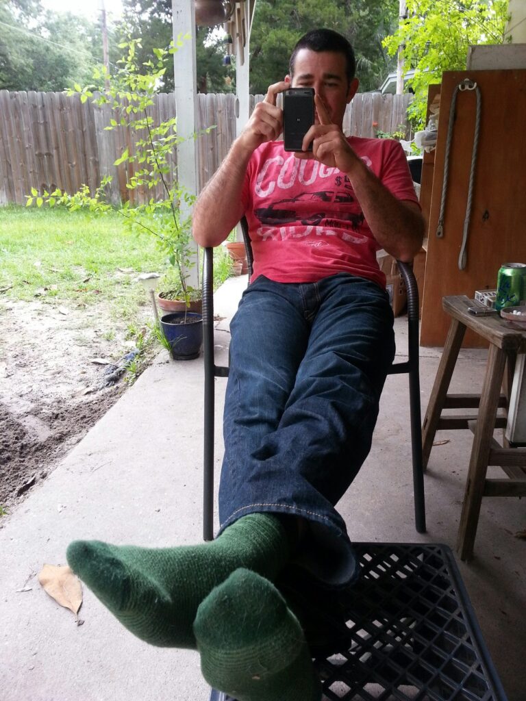 a person sitting on a chair on a patio with their legs stretched out casually