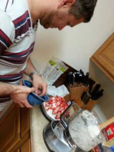 a person is in a kitchen putting the finishing touches on a cake with strawberries