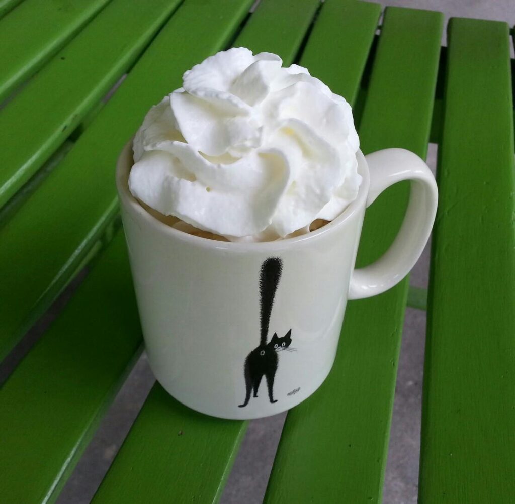 a cup of coffee is piled high with whipped cream