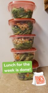 five storage containers are stacked up and filled with what looks like salad