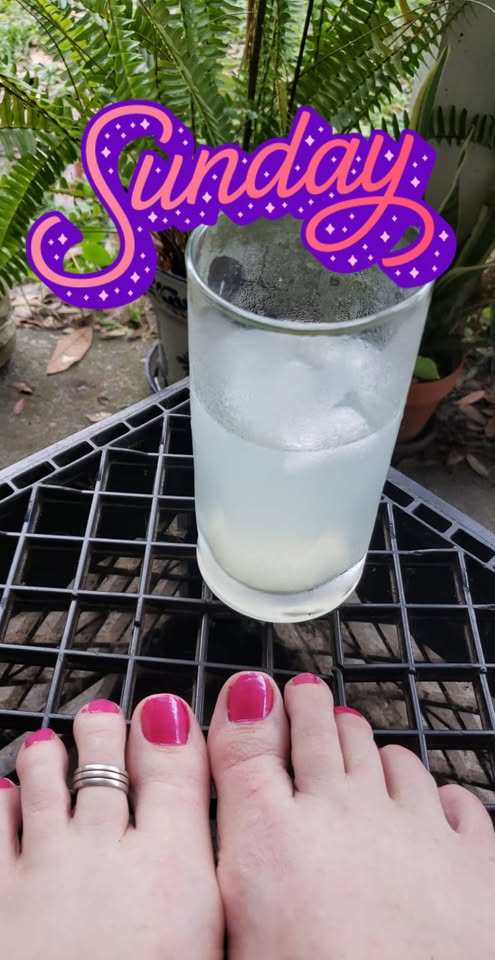 toes are resting on a milk crate next to a glass with a translucent pale drink