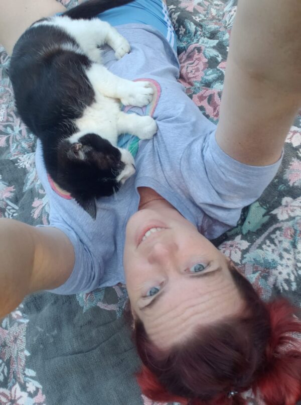 selfie of a person laying on a blanket with a cat sitting on her chest