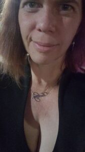 close selfie of a person wearing a black low cut dress